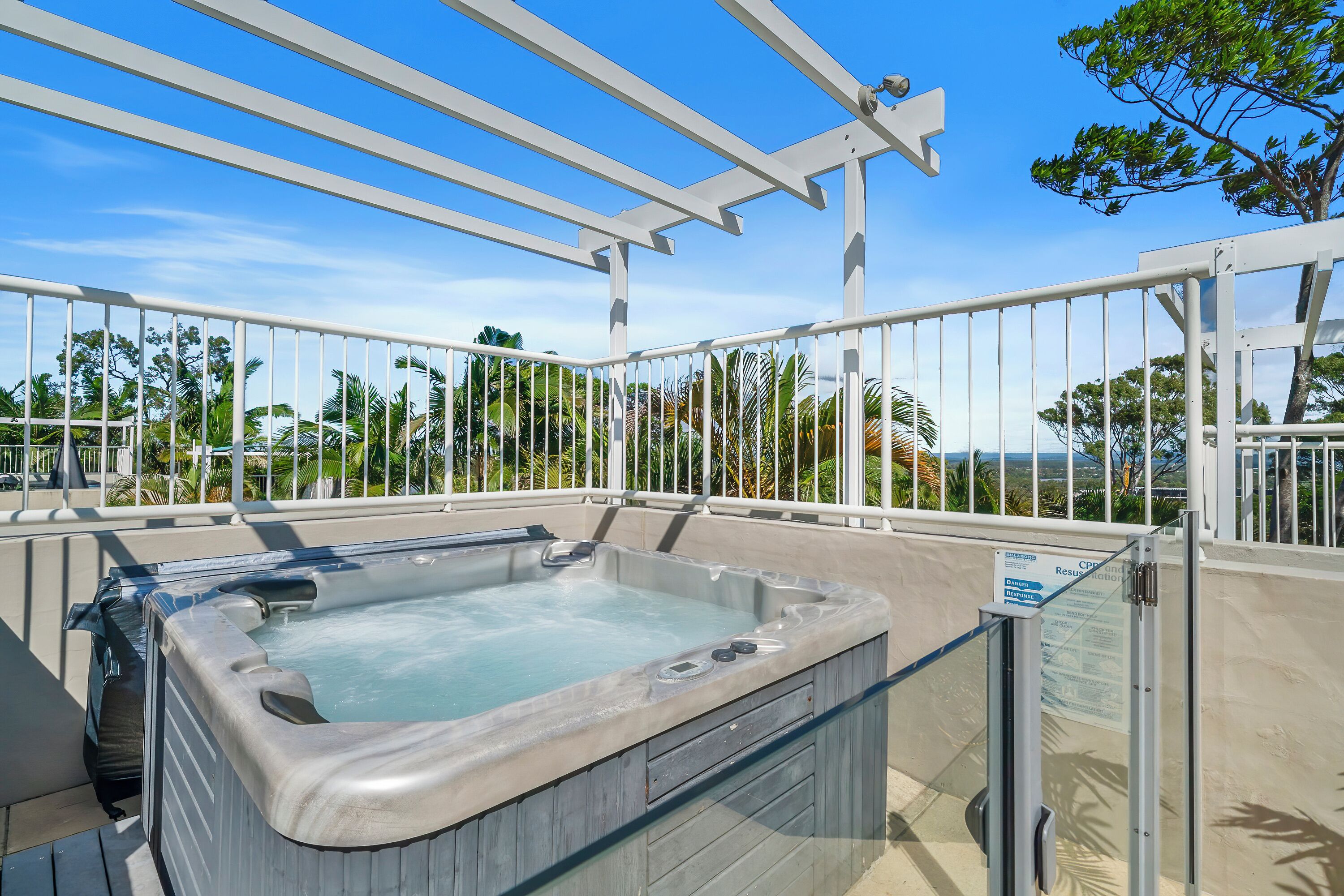 Un jacuzzi con vista a palmeras y un cielo azul despejado.