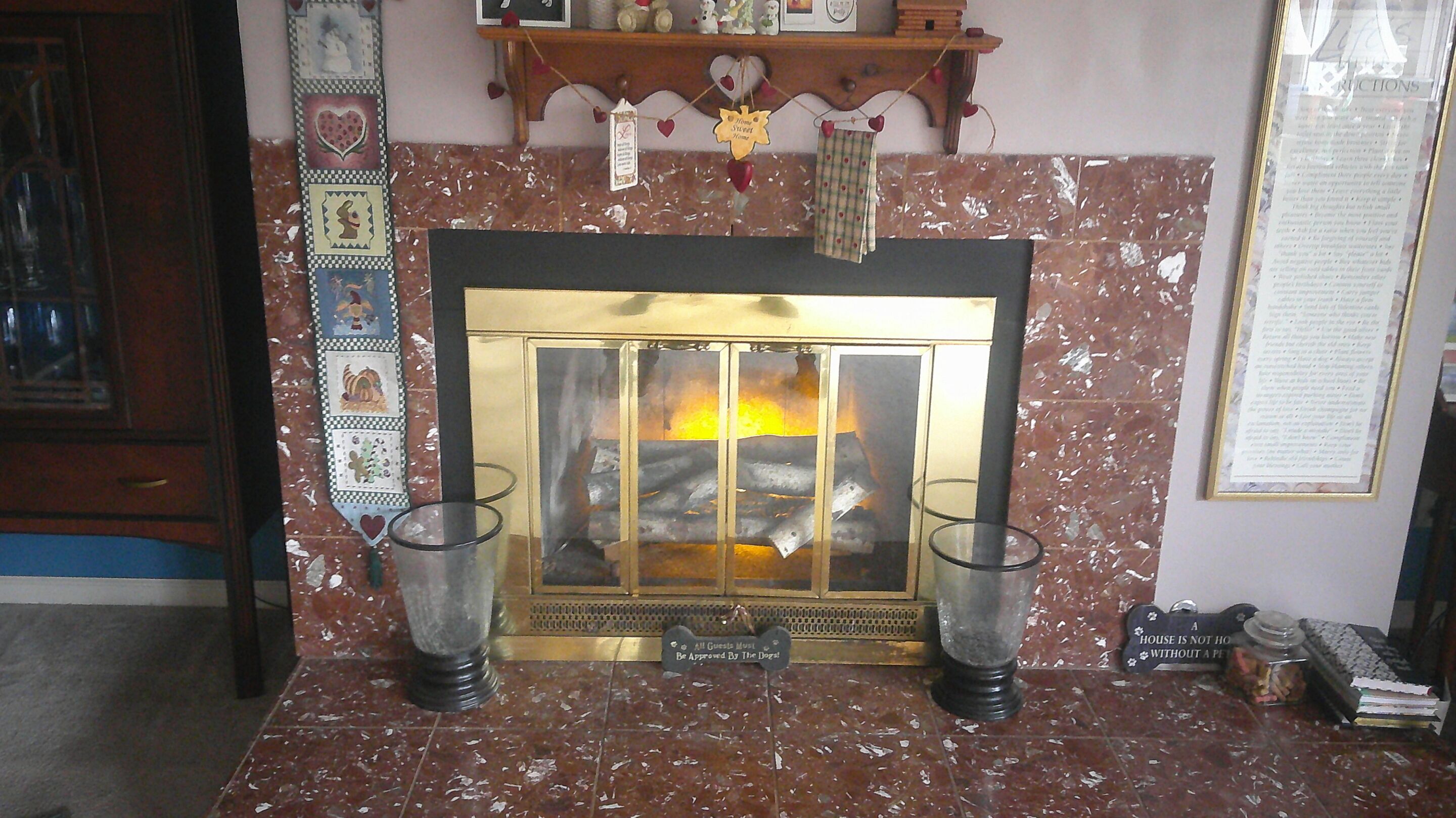A fireplace with a glass door, flanked by two candle holders.