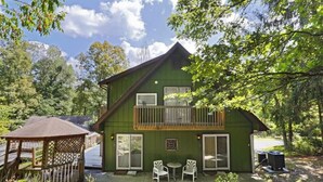 A green house with a balcony, a wooden gazebo, and two chairs outside. - Lil Black Bear Inn (Nashville)