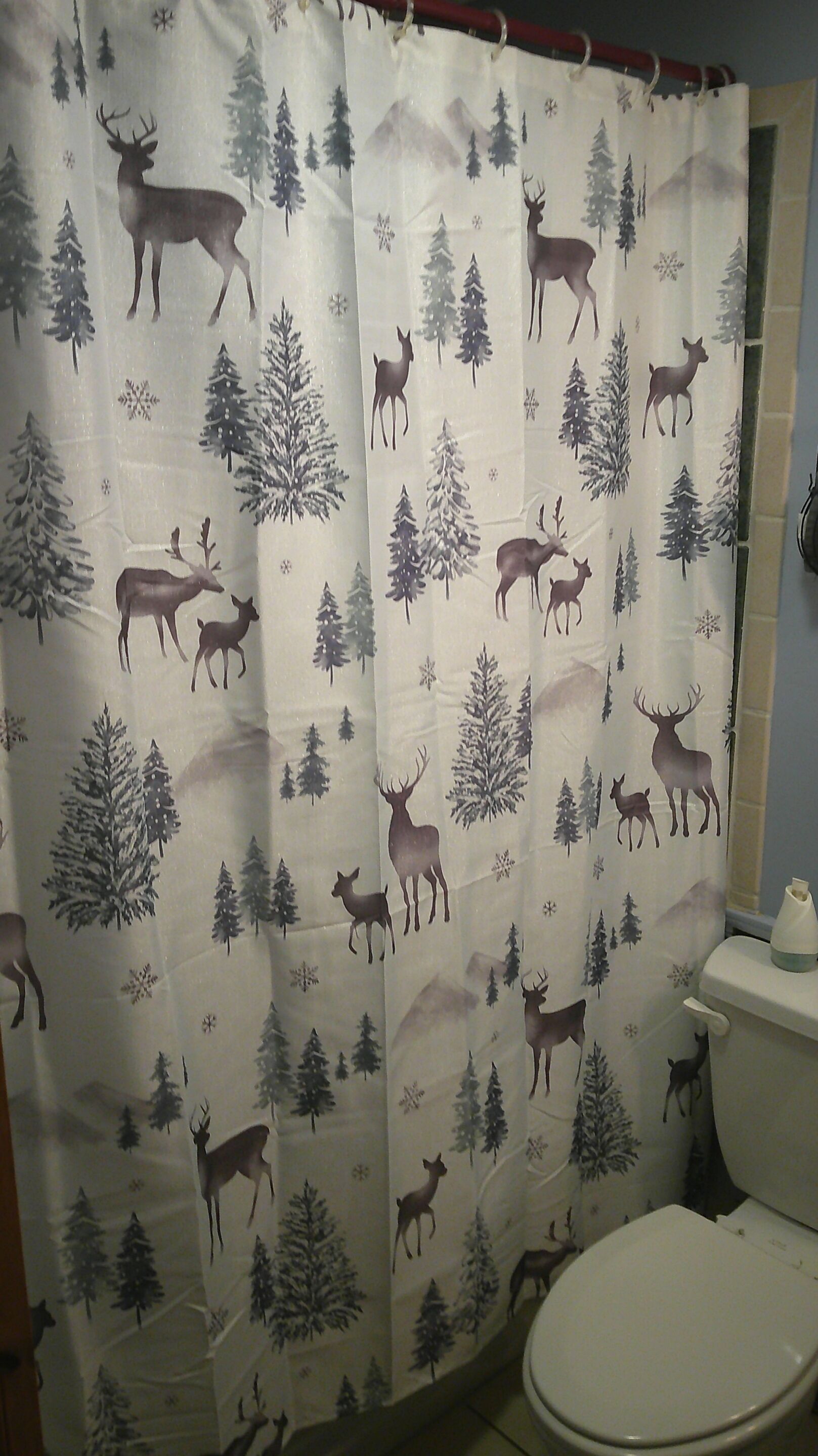 A bathroom with a shower curtain featuring a forest and deer pattern.