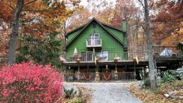 A green building with a balcony, surrounded by autumn foliage. - Lil Black Bear Inn (Nashville)