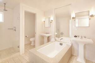 Un baño moderno con una bañera grande, dos lavamanos, un inodoro y una ducha.