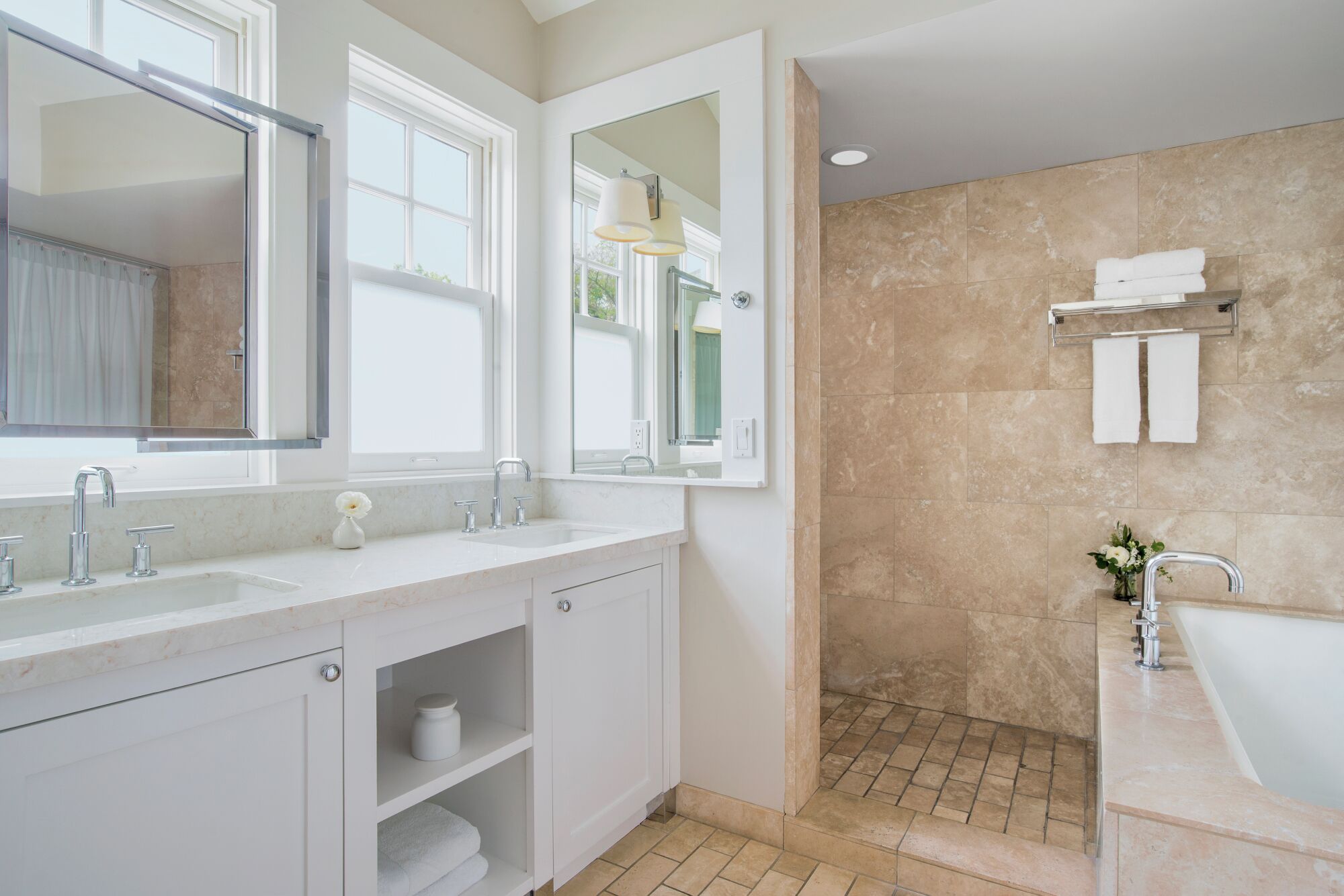 A modern bathroom with two sinks, a large mirror, and a shower area.