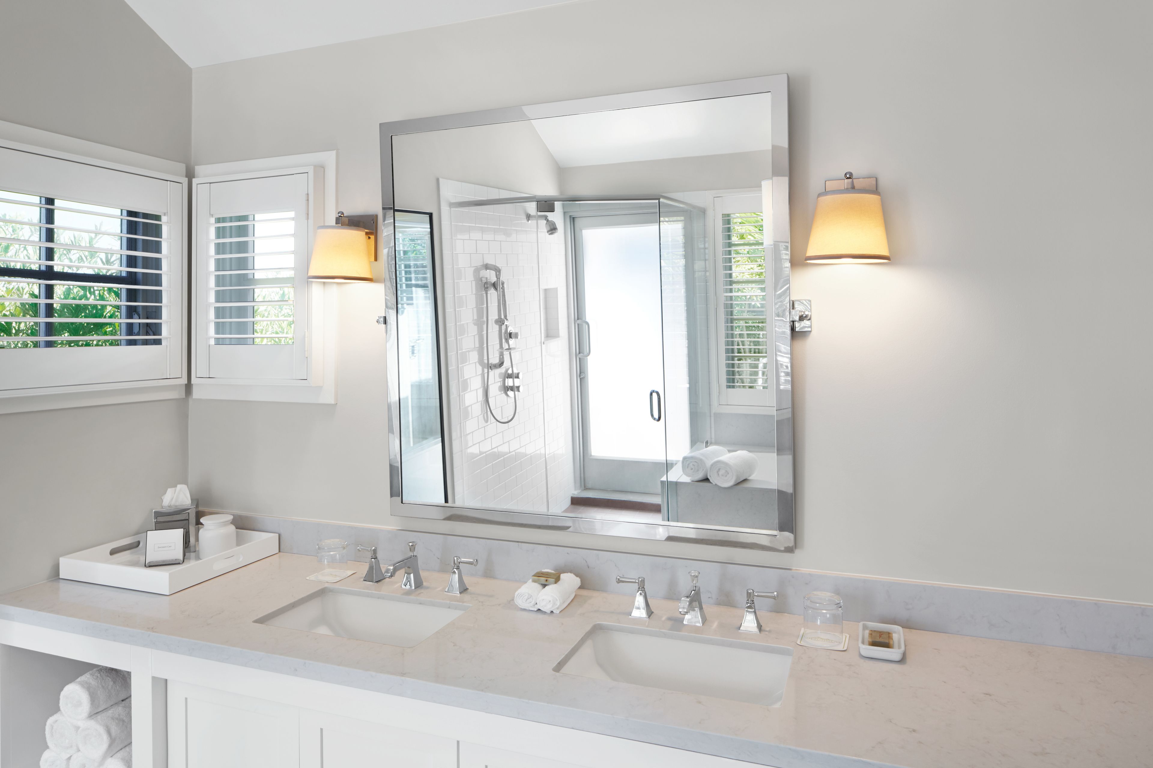 Une salle de bain moderne avec deux lavabos, un grand miroir et un espace douche.