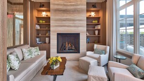 A modern living room with a fireplace, sofas, a coffee table, and bookshelves.