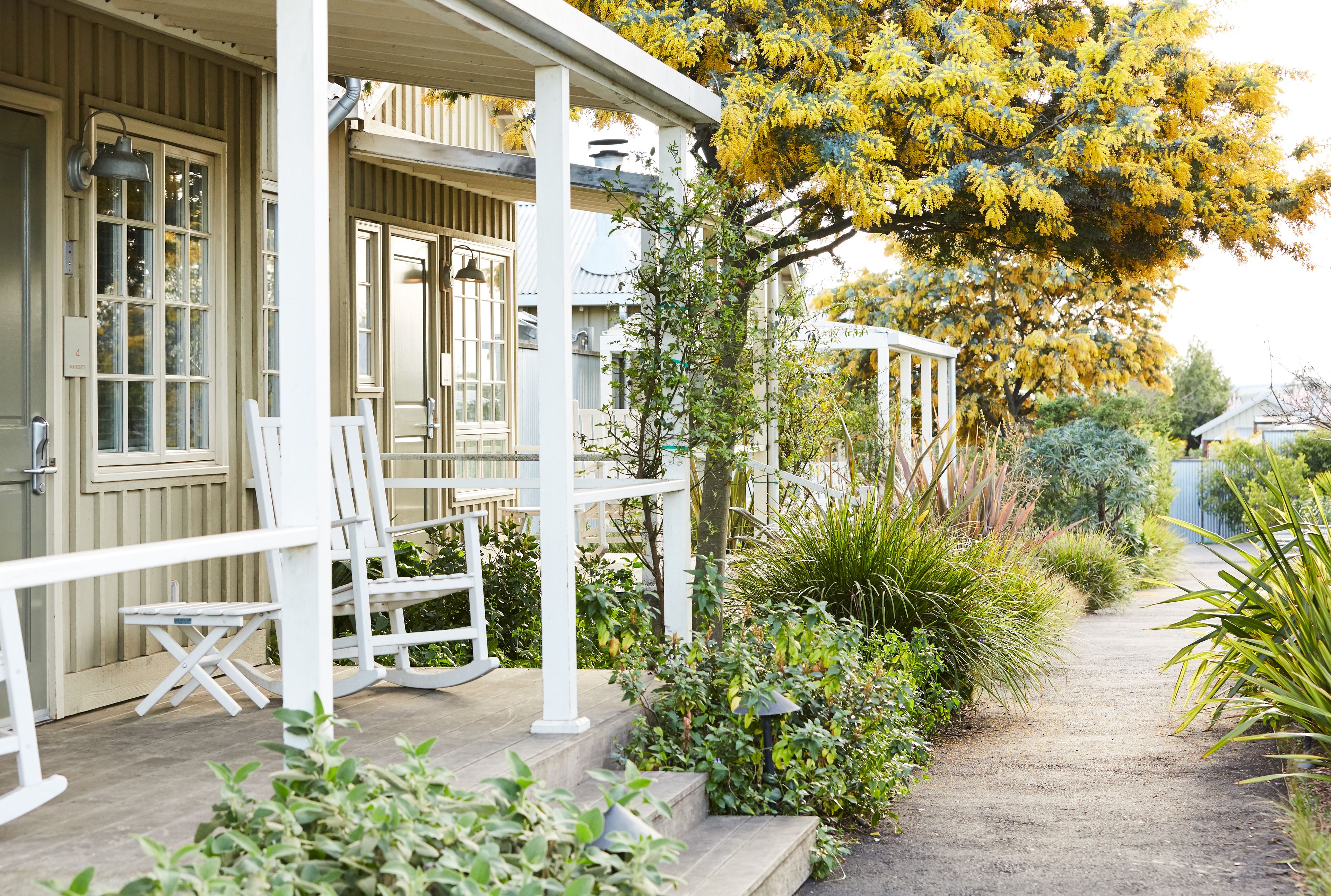 A covered porch with white railings and a small table and chair.