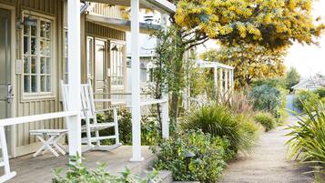 A covered porch with white railings and a small table and chair.
