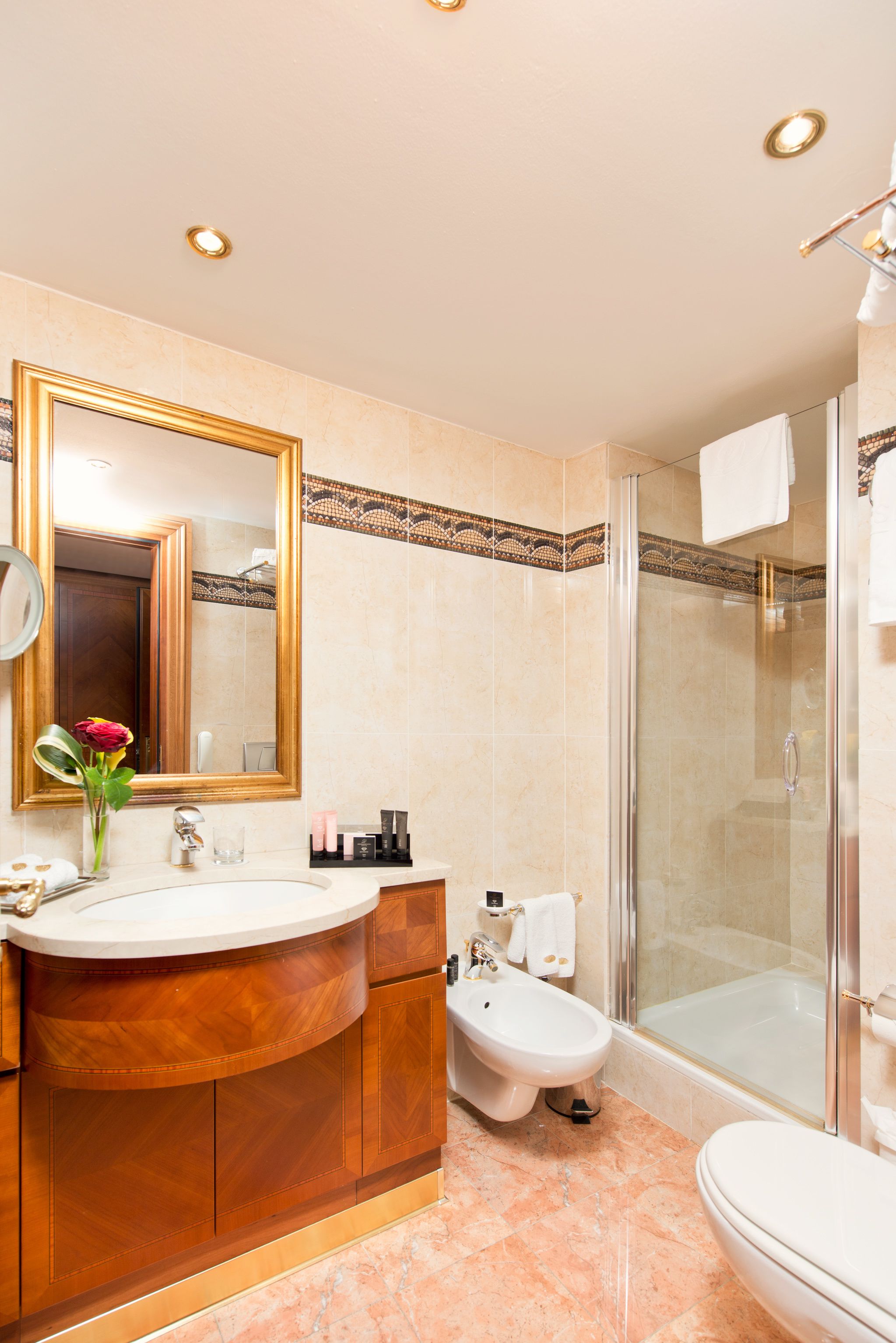 Een badkamer met een wastafel, wastafelmeubel, spiegel, toilet en douche.