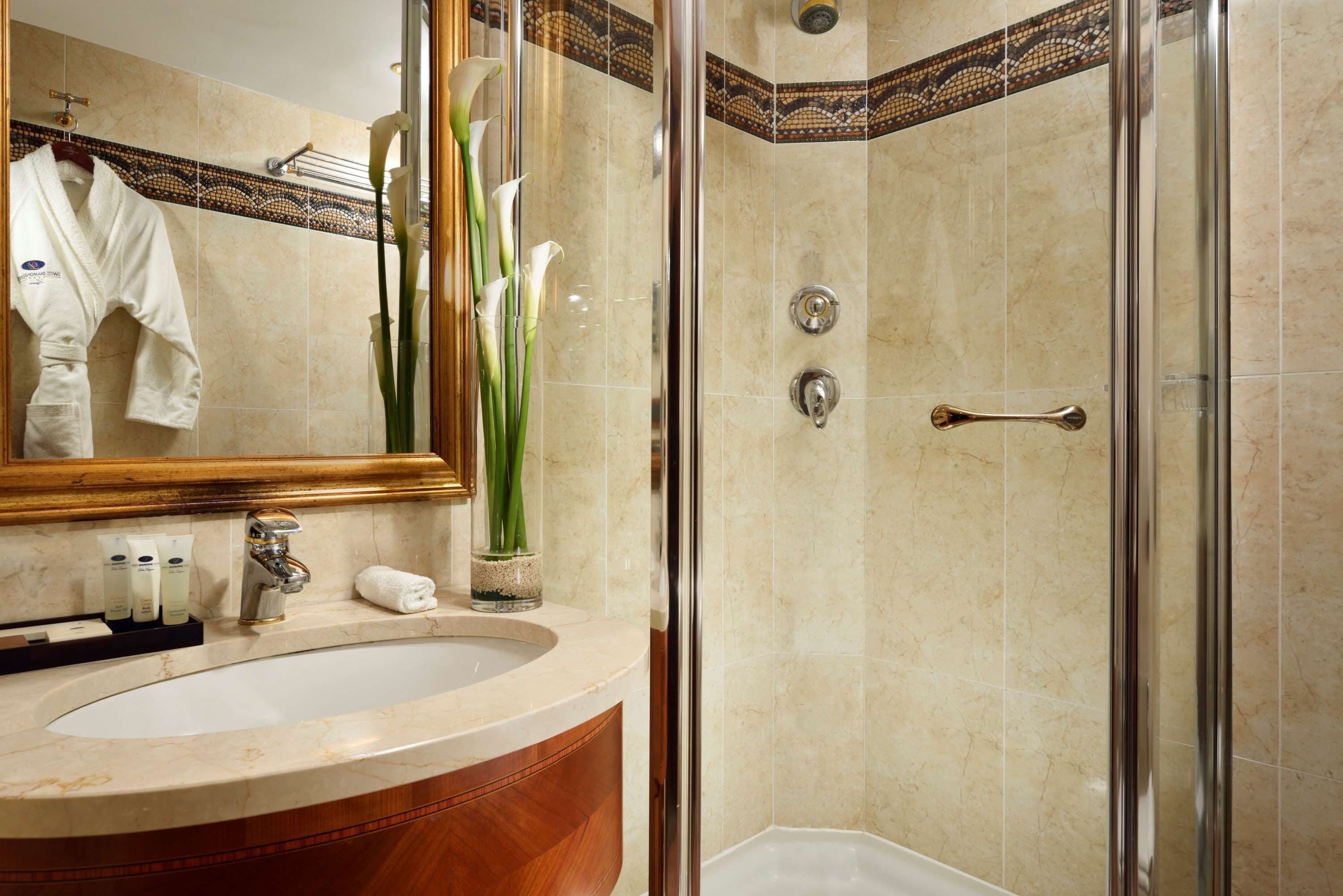 A bathroom with a marble sink, a glass-enclosed shower, and a mirror with a towel rack.