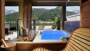 Et værelse med en træbænk, jacuzzi og et bord med snacks og en drik.