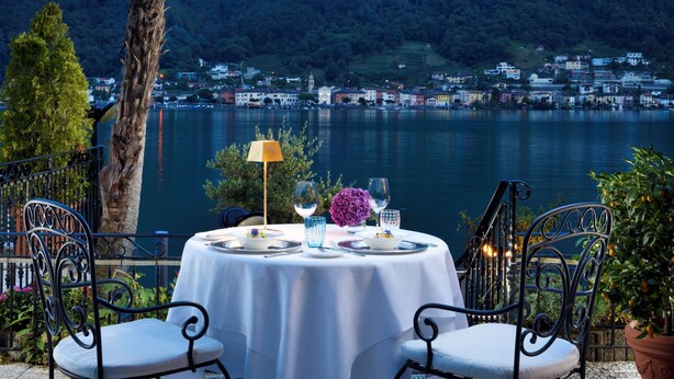 Ein Tisch für zwei Personen mit Blick auf einen See und eine Stadt im Hintergrund.
