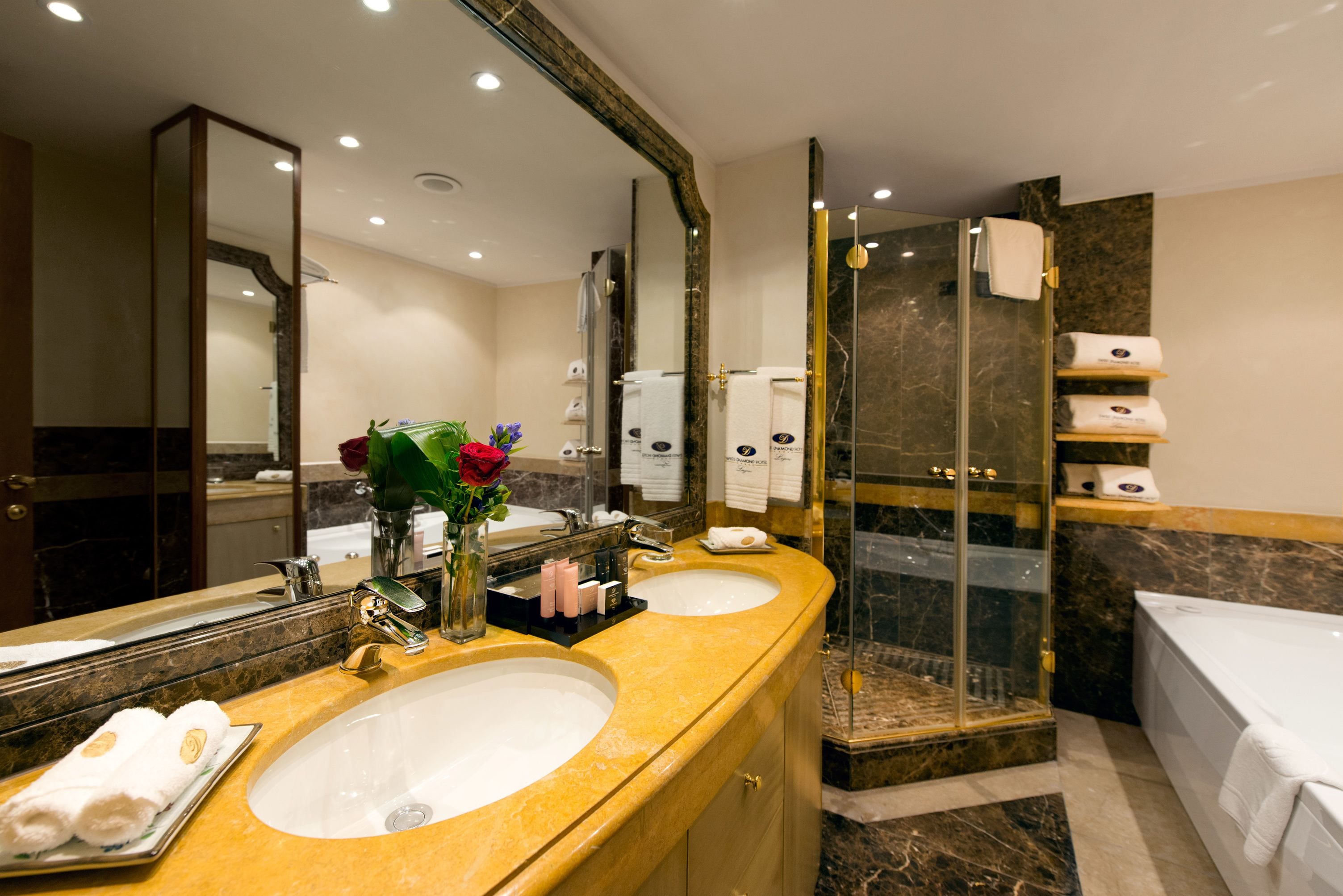 A bathroom with two sinks, a large mirror, a glass-enclosed shower, and a bathtub.