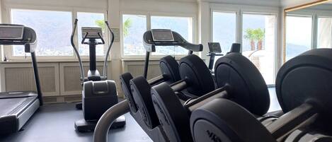 Ein Fitnessstudio mit Laufbändern, Crosstrainern und Hantelbänken.