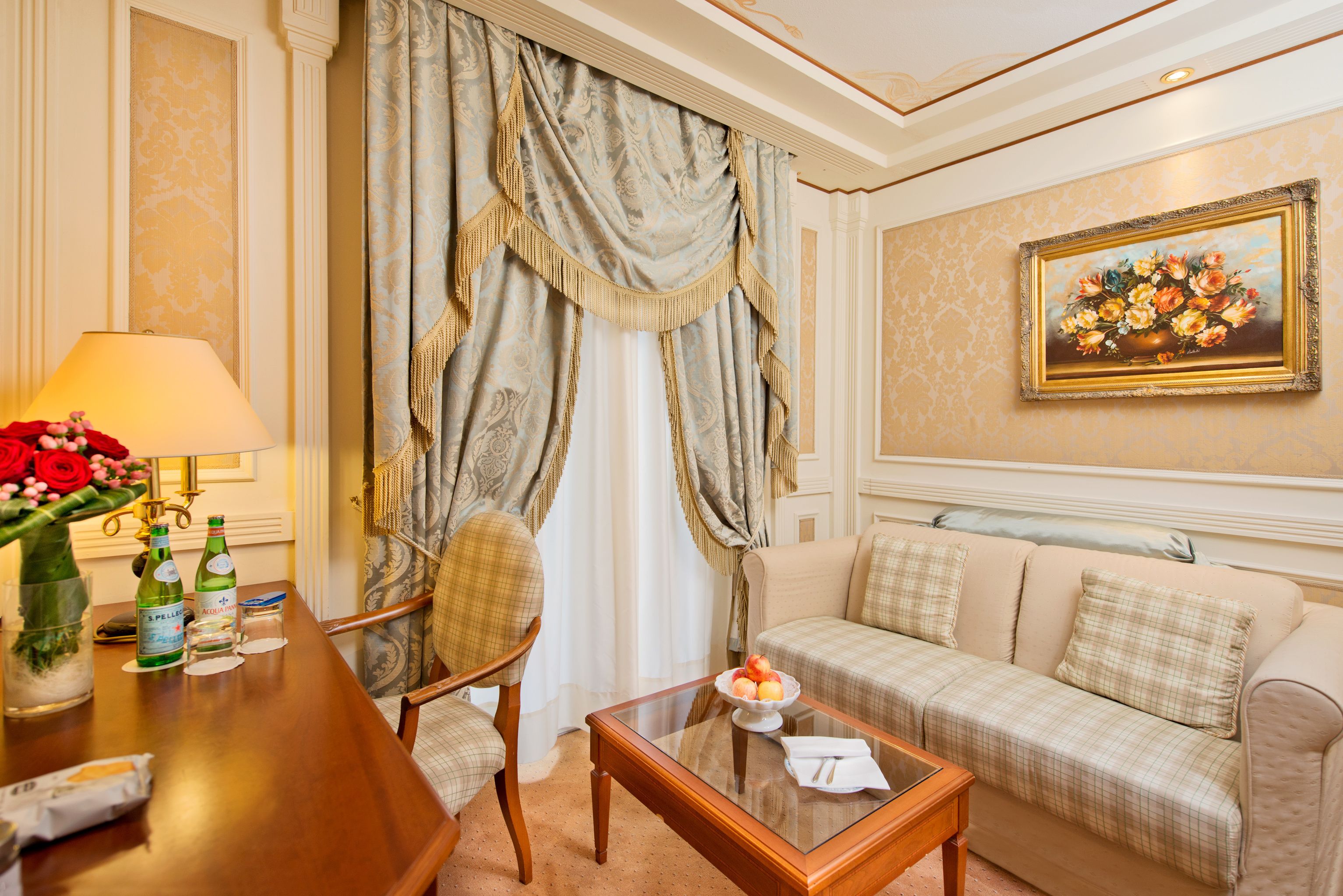 Une chambre d’hôtel avec une table basse en bois, un canapé, un fauteuil, une lampe et un tableau au mur.