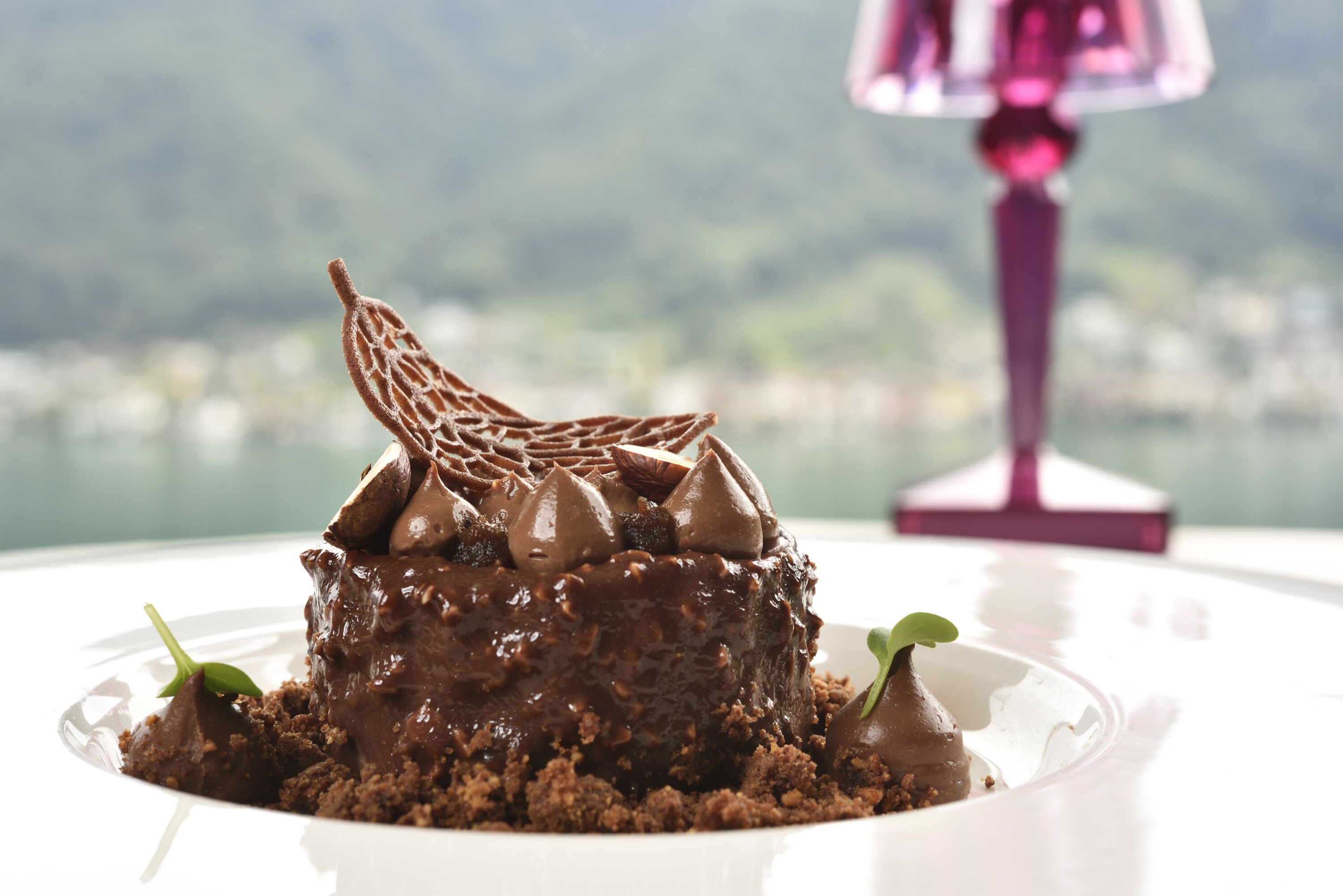 Ein Schokoladendessert auf einem weißen Teller, im Hintergrund eine schöne Aussicht.