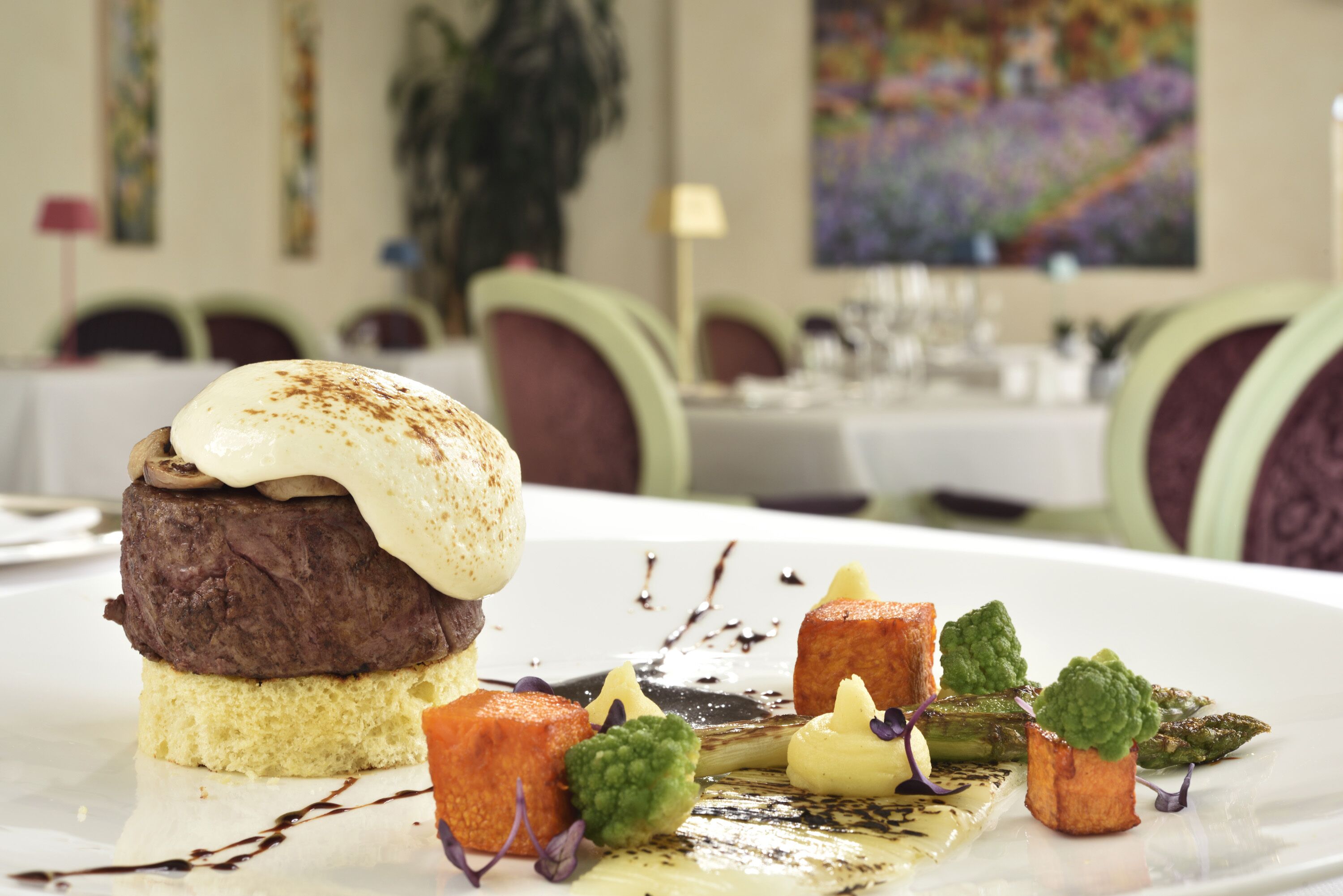 A dessert with a layered cake and a scoop of ice cream on top, accompanied by small garnishes and sauces on a white plate.