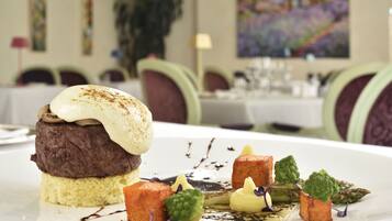 A dessert with a layered cake and a scoop of ice cream on top, accompanied by small garnishes and sauces on a white plate.