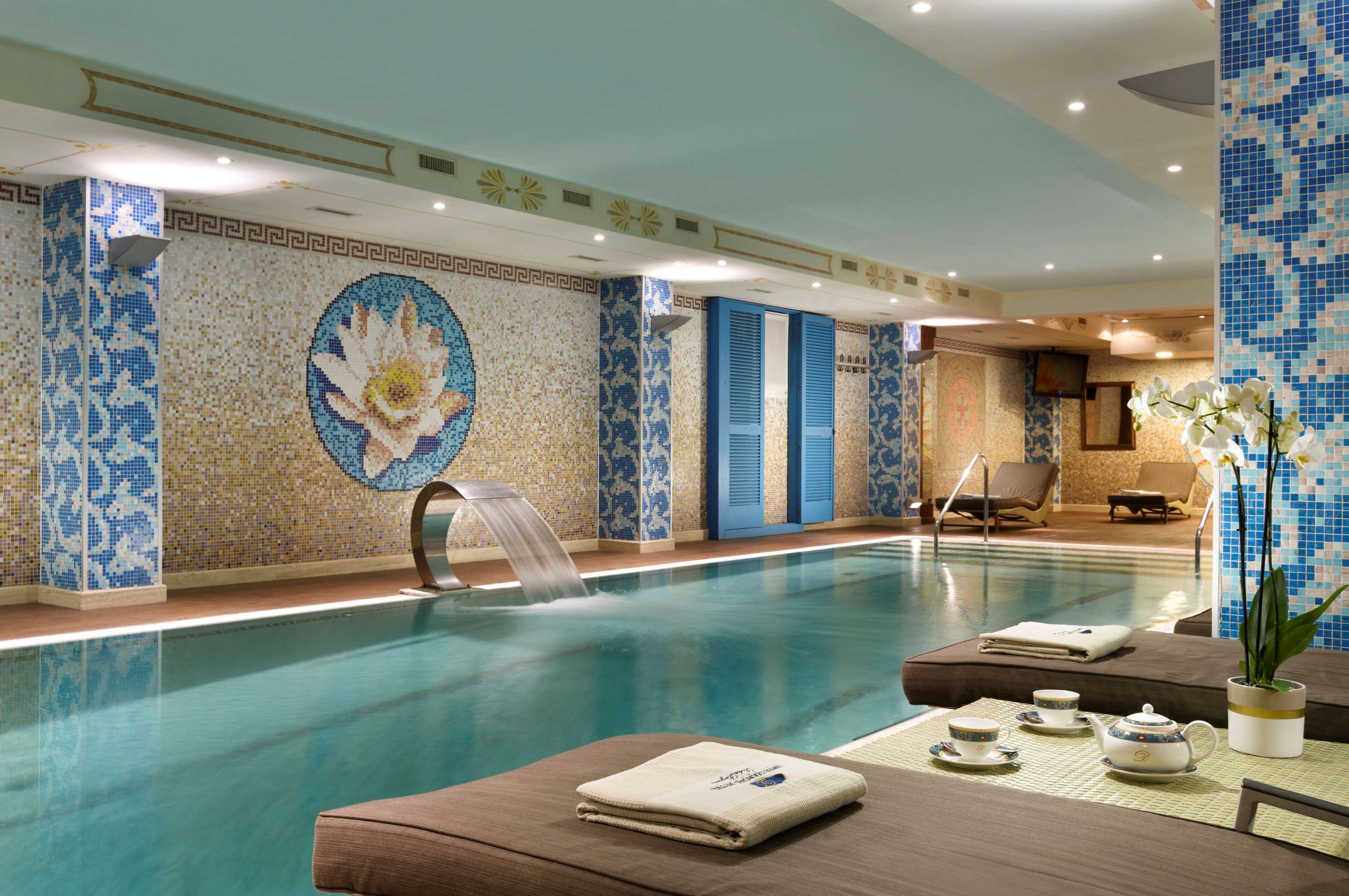 Ein Swimmingpool mit Wasserspiel, Liegestühlen und einer Sitzecke mit nachgestelltem Tisch für Tee.