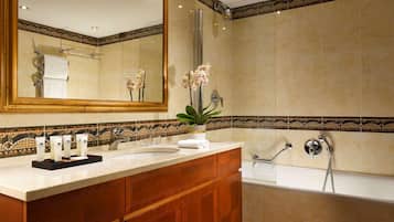 Ein modernes Badezimmer mit großem Spiegel, zwei Waschbecken, einer Badewanne und einer dekorativen Fliesenzierleiste.