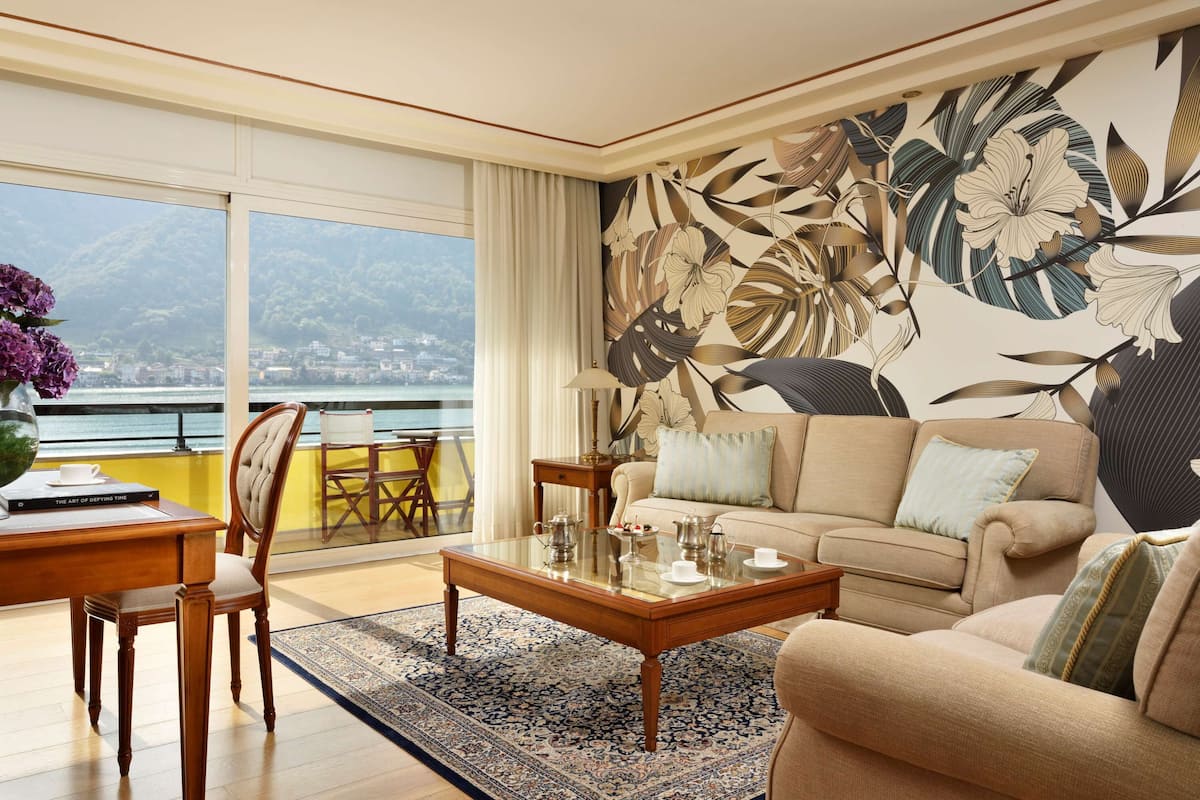 Uma sala de estar com uma janela ampla, um sofá, uma mesa de centro e um mural floral na parede.