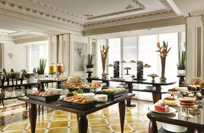 A spacious hotel dining area with multiple tables set for a buffet, featuring a variety of food items and elegant decor. - Swiss Diamond Hotel & SPA (Vico Morcote)