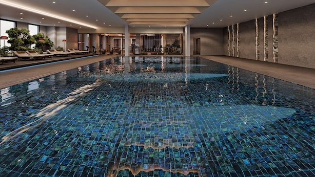 Una amplia piscina cubierta con suelo de baldosas, rodeada de zonas de descanso y equipo de ejercicio.