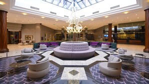 Un hall d’entrée spacieux avec un espace salon central, un lustre et un plafond haut doté de lucarnes.