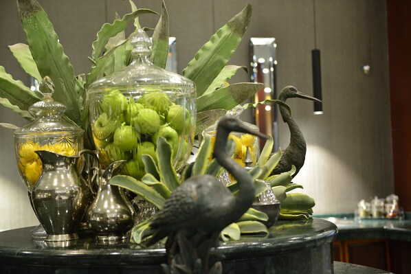 Une composition décorative comprenant des bocaux en verre, des plantes vertes et une sculpture d’oiseau, le tout disposé sur une surface en marbre.