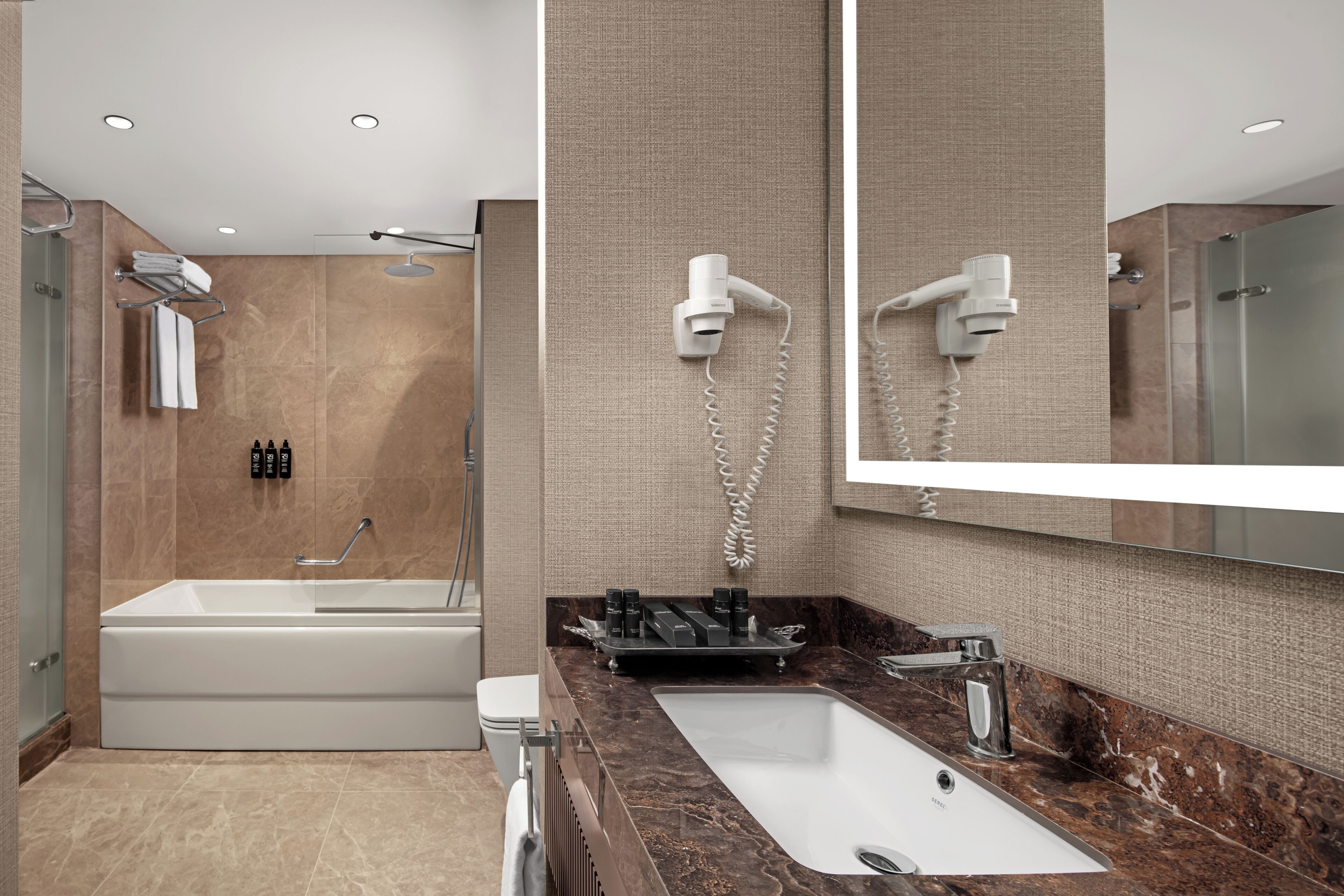 A modern bathroom with a bathtub, a sink, and a large mirror.