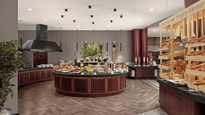 Una cocina moderna con una isla central, armarios de madera y una vitrina de pastelería.