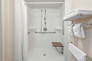 Enjoy a refreshing shower experience with a clear glass door, handheld showerhead, and convenient bench for seating.