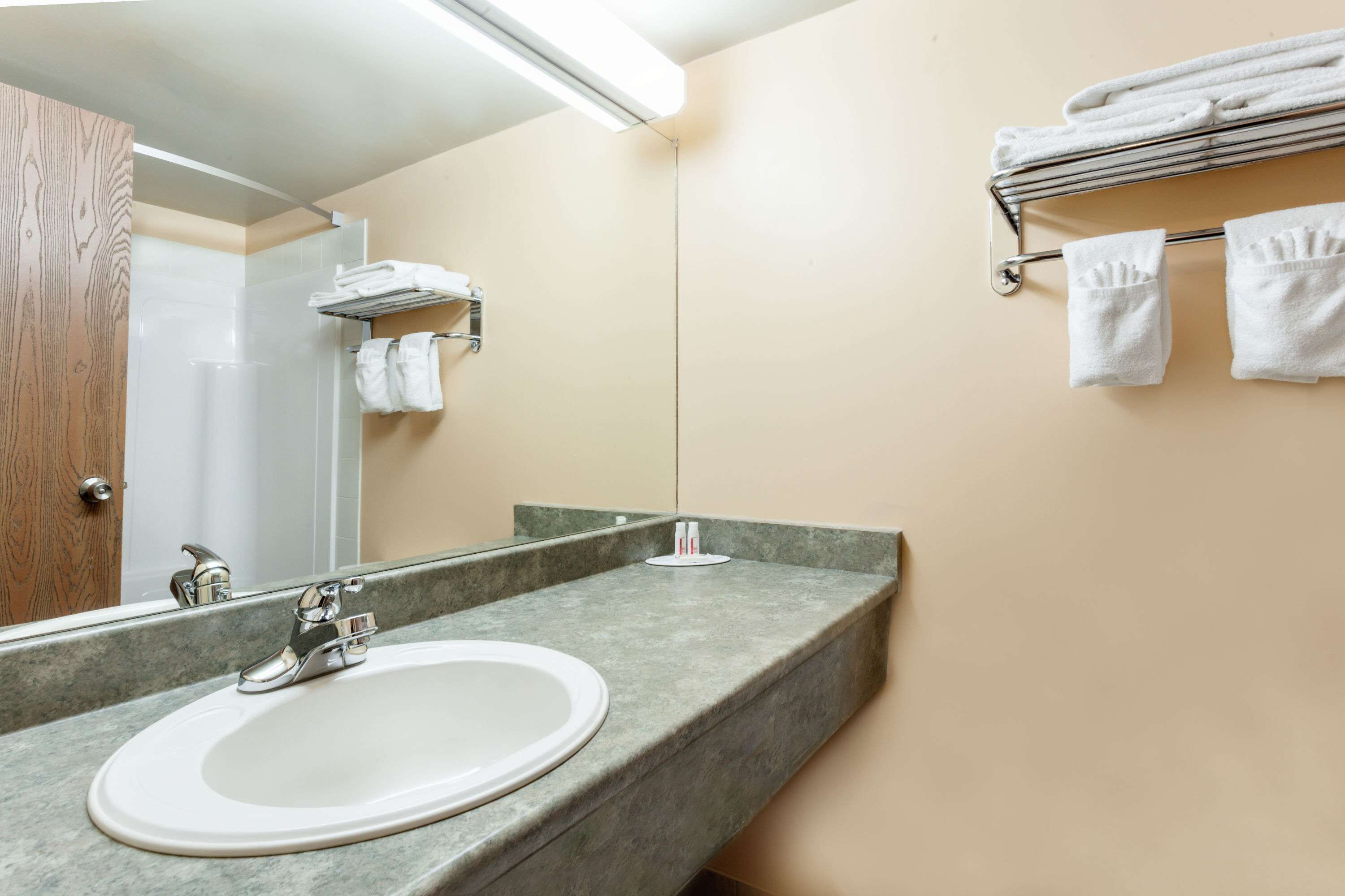 Une salle de bain équipée d’un lavabo, d’un miroir, d’un porte-serviettes et d’un espace douche.