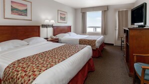 Habitación de hotel con dos camas, un escritorio con televisor y una ventana con vistas.