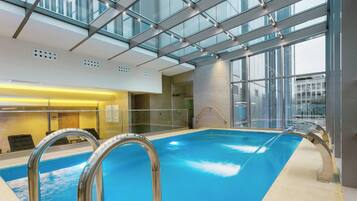 Une piscine intérieure aux murs de verre, à l’eau d’un bleu limpide, et dotée d’une architecture moderne.