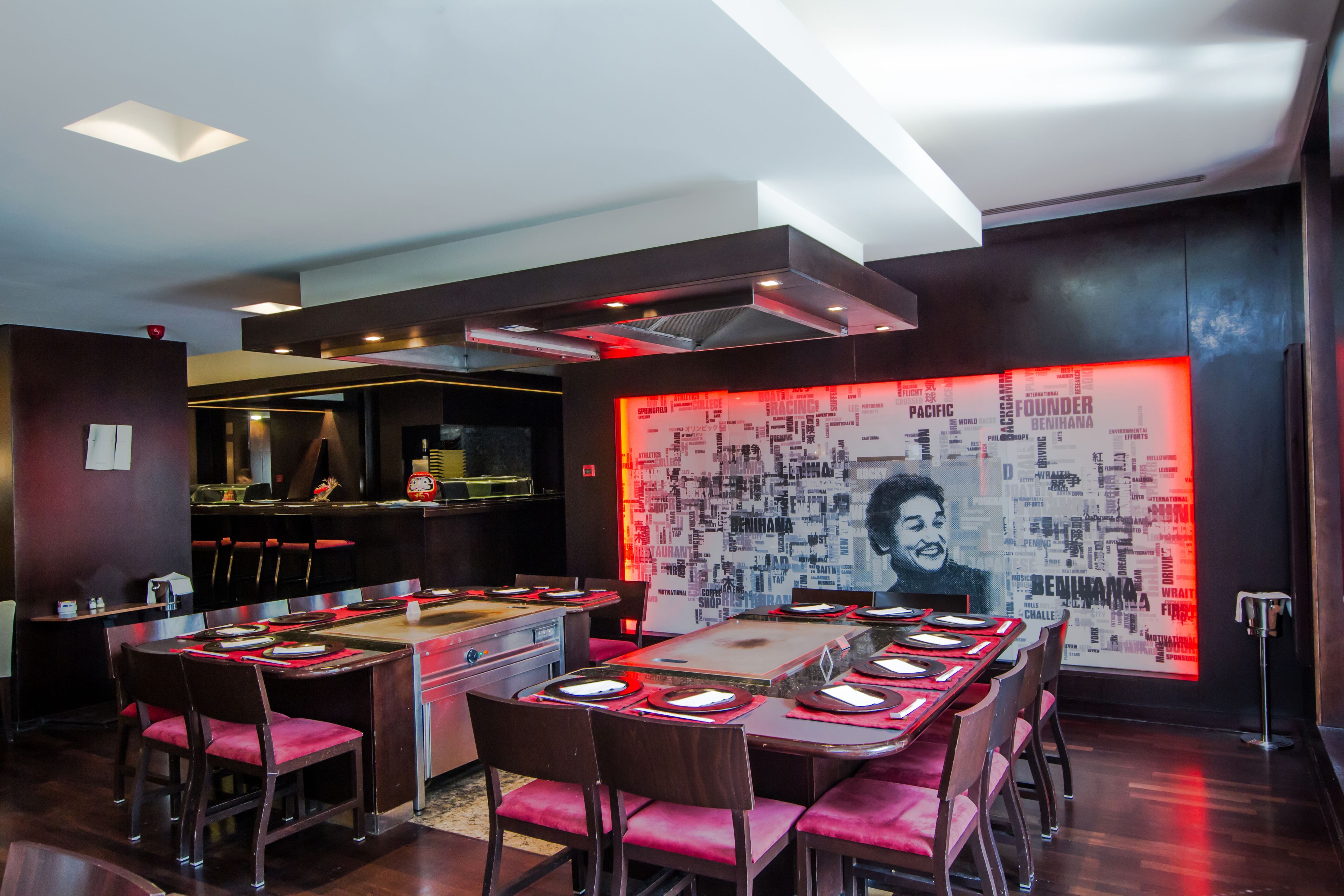 A restaurant with a long communal table, individual booths, and a wall with a large poster.