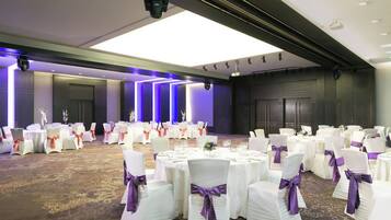 A banquet hall with round tables, chairs, and a carpeted floor.
