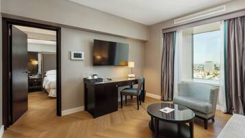 A hotel room with a desk, chair, and a bed.