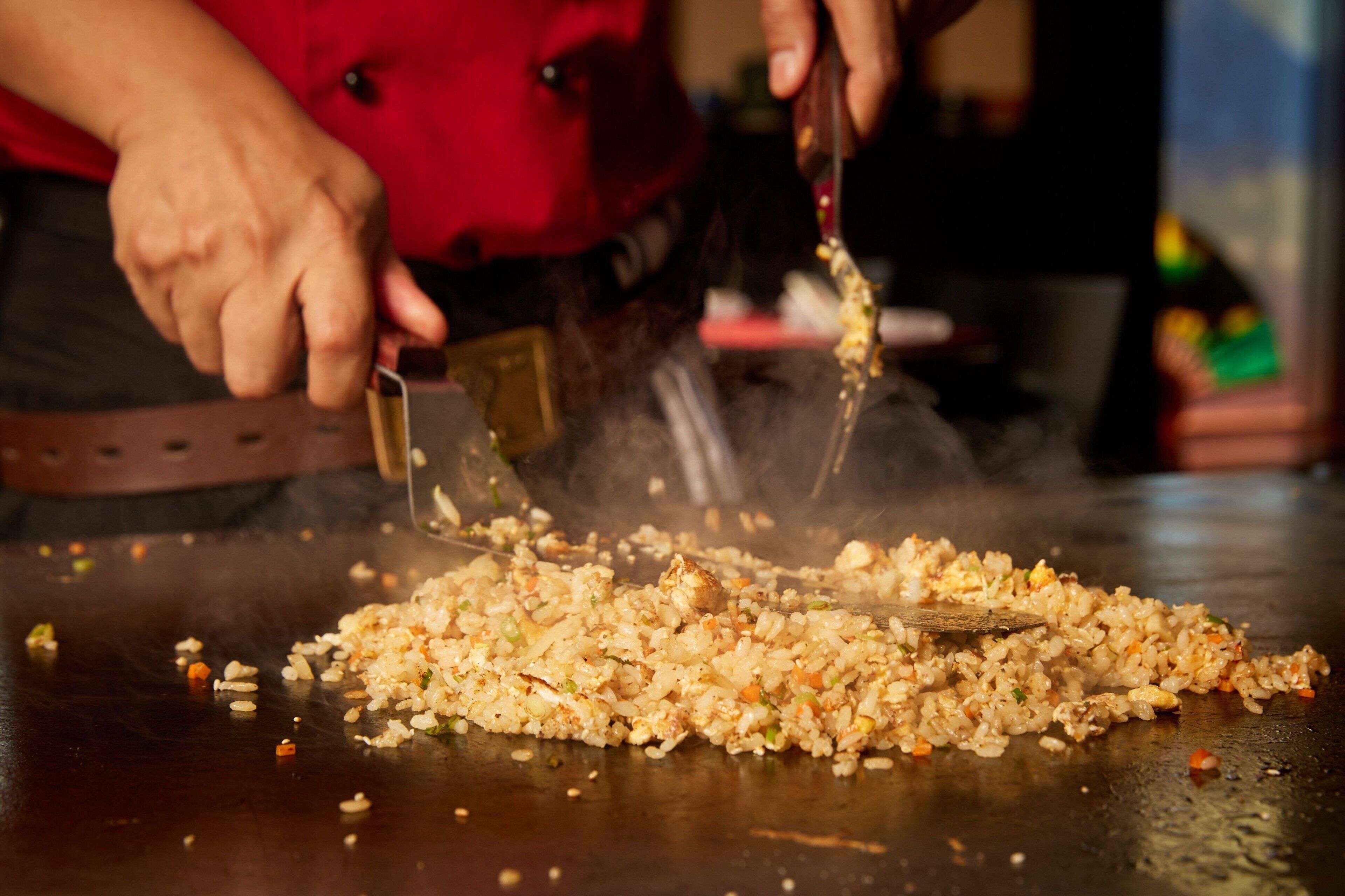A person cooking on a hot griddle, likely preparing a dish.