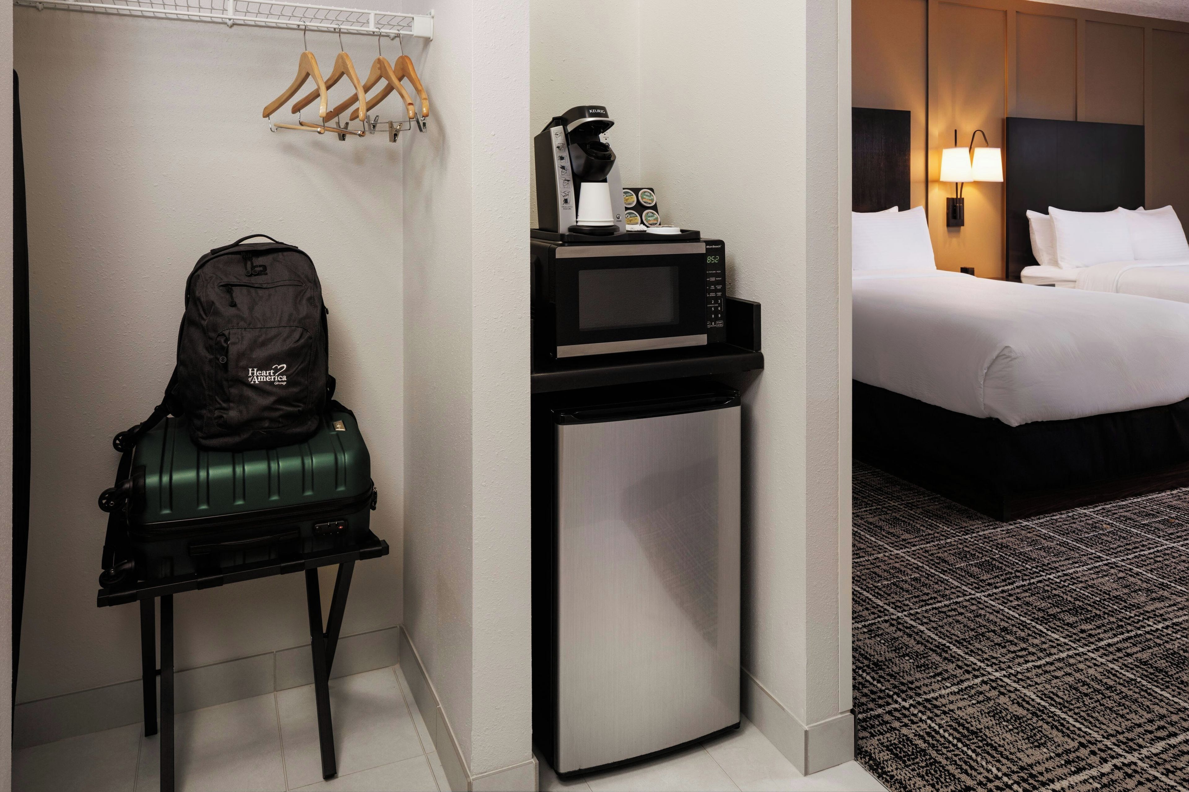 Una kitchenette compacta con microondas, cafetera y refrigerador pequeño.