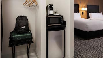Una kitchenette compacta con microondas, cafetera y refrigerador pequeño.