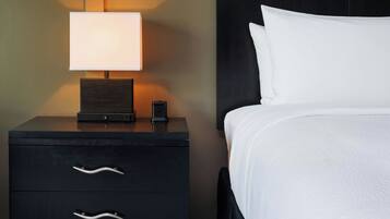 Ein Hotelzimmer mit einem Bett, einem Nachttisch mit Lampe und zwei Schubladen.
