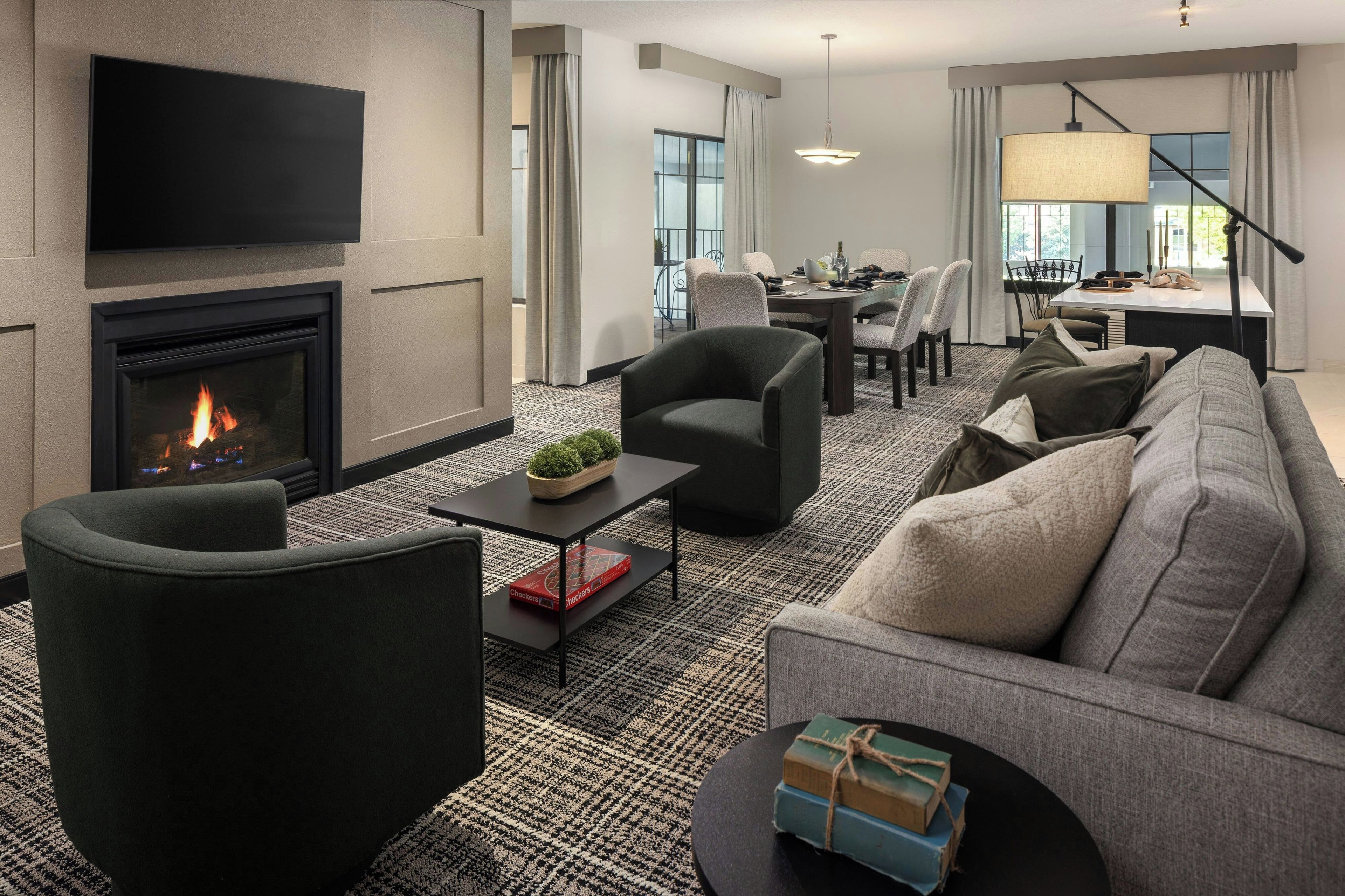 A modern living room with a fireplace, comfortable seating, a flat-screen TV, and a dining area.