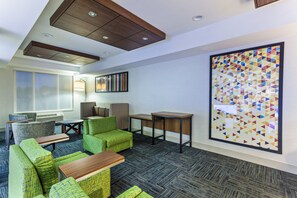 A hotel lobby with seating, a large artwork, and a ceiling with recessed lighting. - Holiday Inn Express & Suites Elk Grove West I-5 by IHG (Elk Grove)