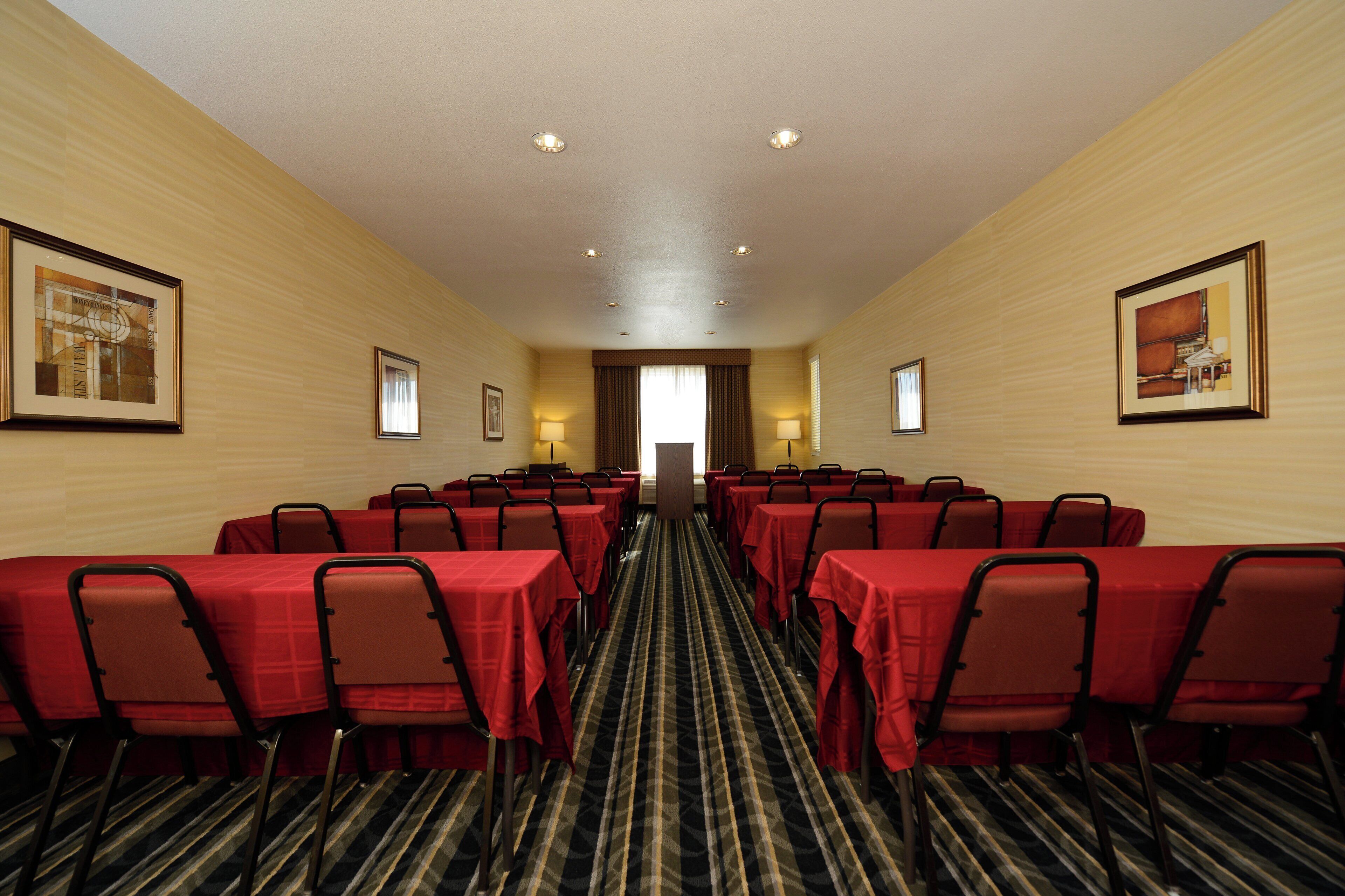 A conference room with tables and chairs, a carpeted floor, and framed pictures on the walls.