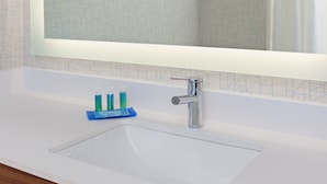 Un baño con lavamanos blanco, un espejo y un grifo.