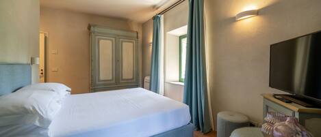 Quarto de hotel com uma cama, televisão e um vaso sobre uma mesa.