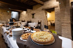 A buffet table with various dishes and a large apple tart in the foreground.