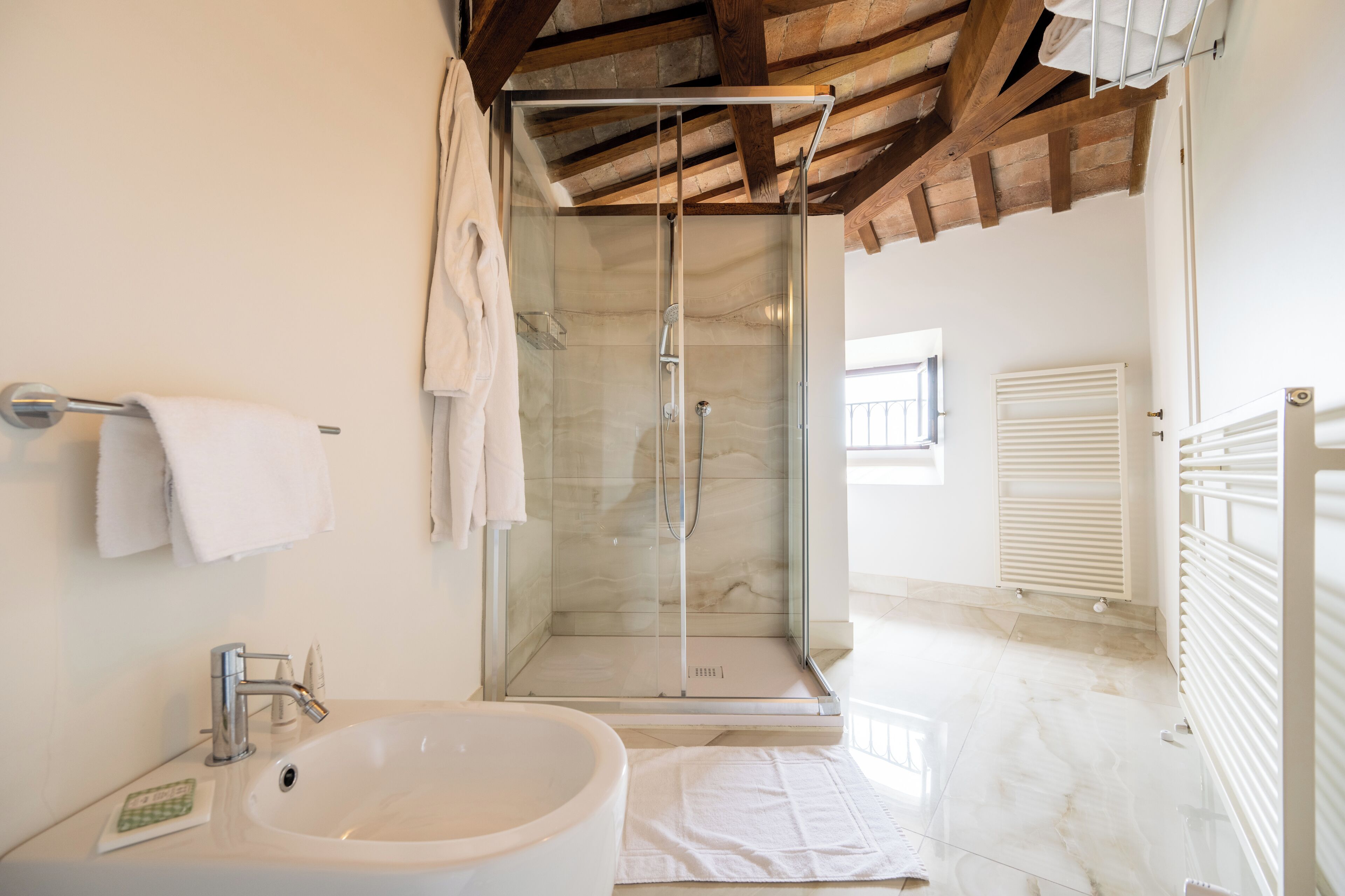 Une salle de bain moderne avec une douche à parois de verre, une grande baignoire et un sol carrelé de couleur blanche.