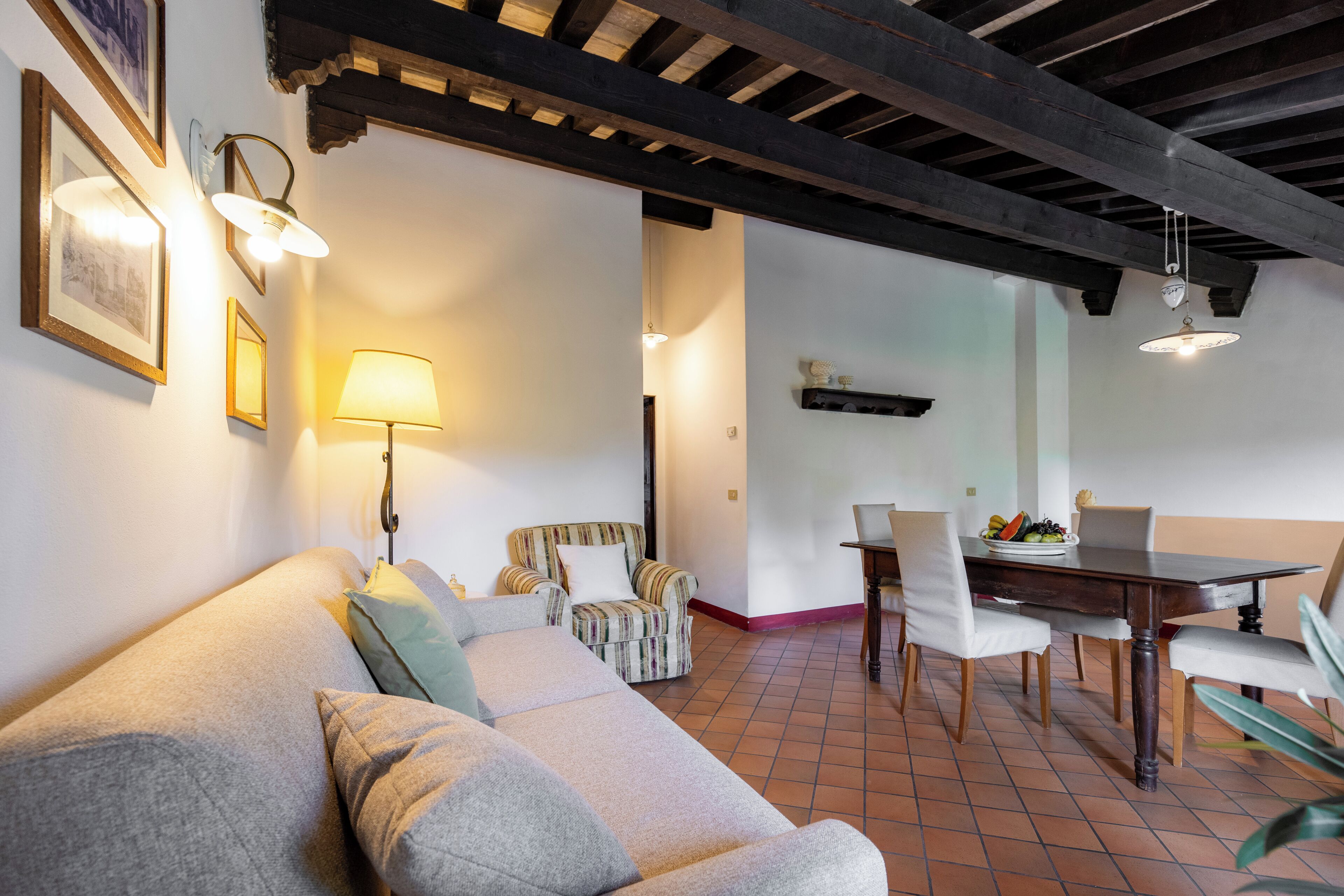 Un salon comprenant un canapé, des fauteuils, une table à manger avec des chaises et une lampe.