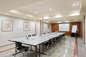 Uma sala de conferência com uma mesa comprida, cadeiras, tela de projetor e obras de arte emolduradas nas paredes.